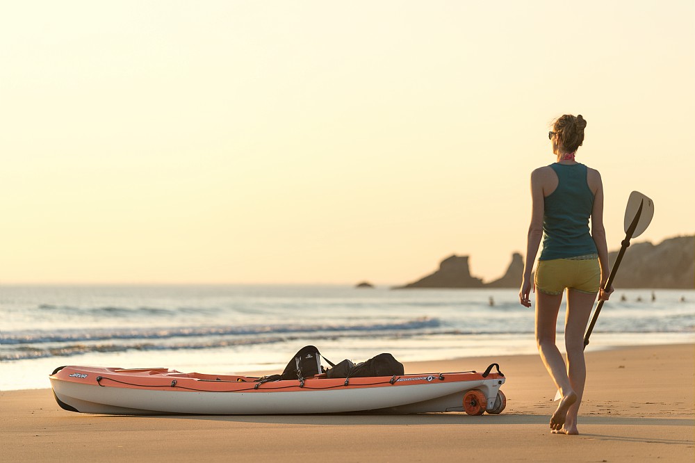 Femme sur une plage au bord de l'eau au coucher de soleil prête à partir en kayak - Baie de Quiberon